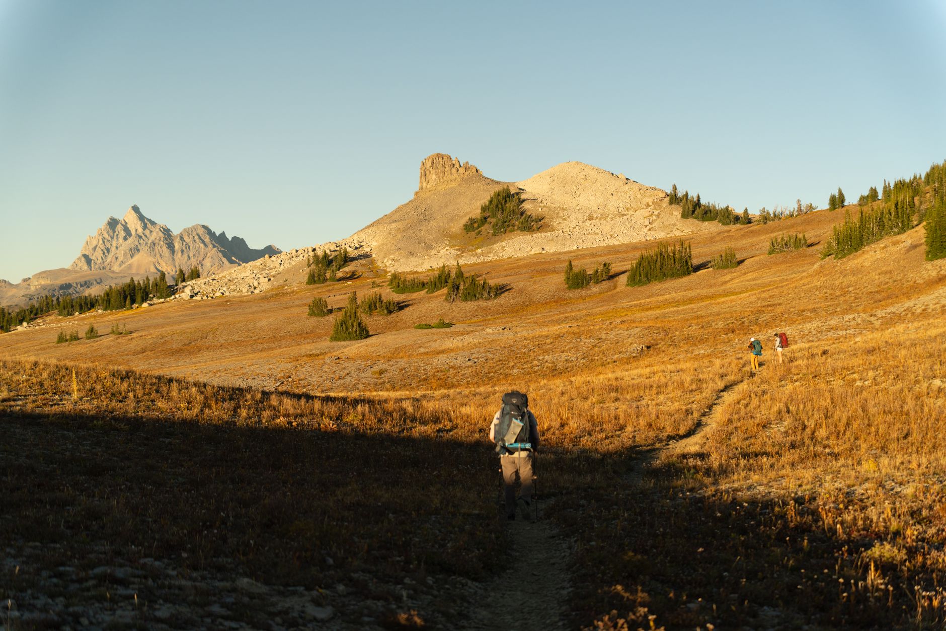 Hikers traverse the Grand Teton landscape at golden hour