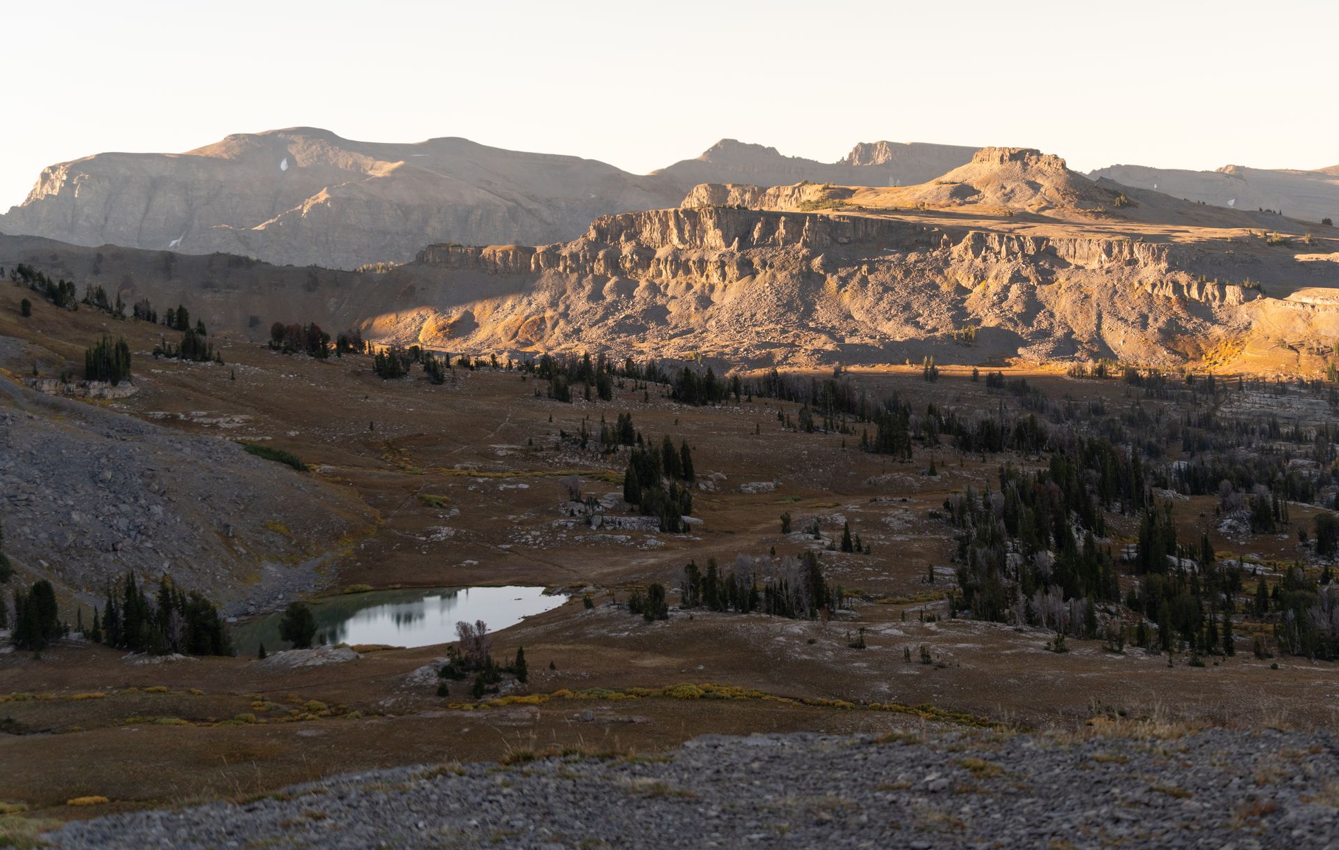 Capture of the majestic Wyoming landscape at sunset with rugged mountains and serene lake.
