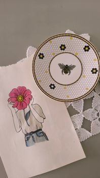 Artistic still life featuring a bee plate and flower illustration on fabric.. artistic, still, life