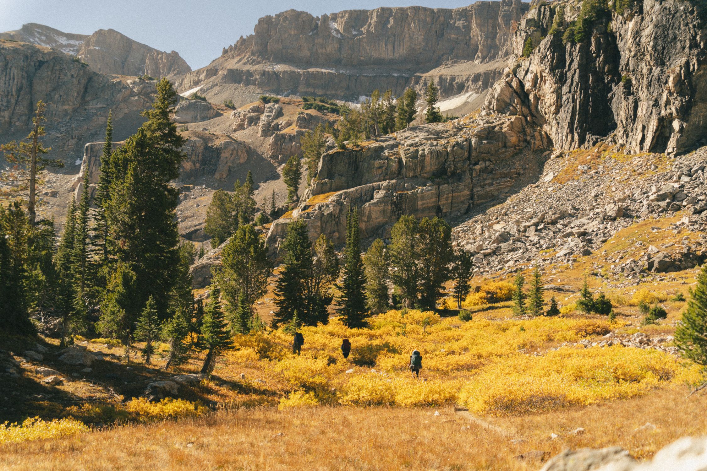 Hikers traverse the vibrant autumn scenery of Grand Teton National Park, Wyoming.