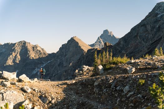 A hiker traverses rocky terrain with mountains in Wyoming's Grand Teton National Park.