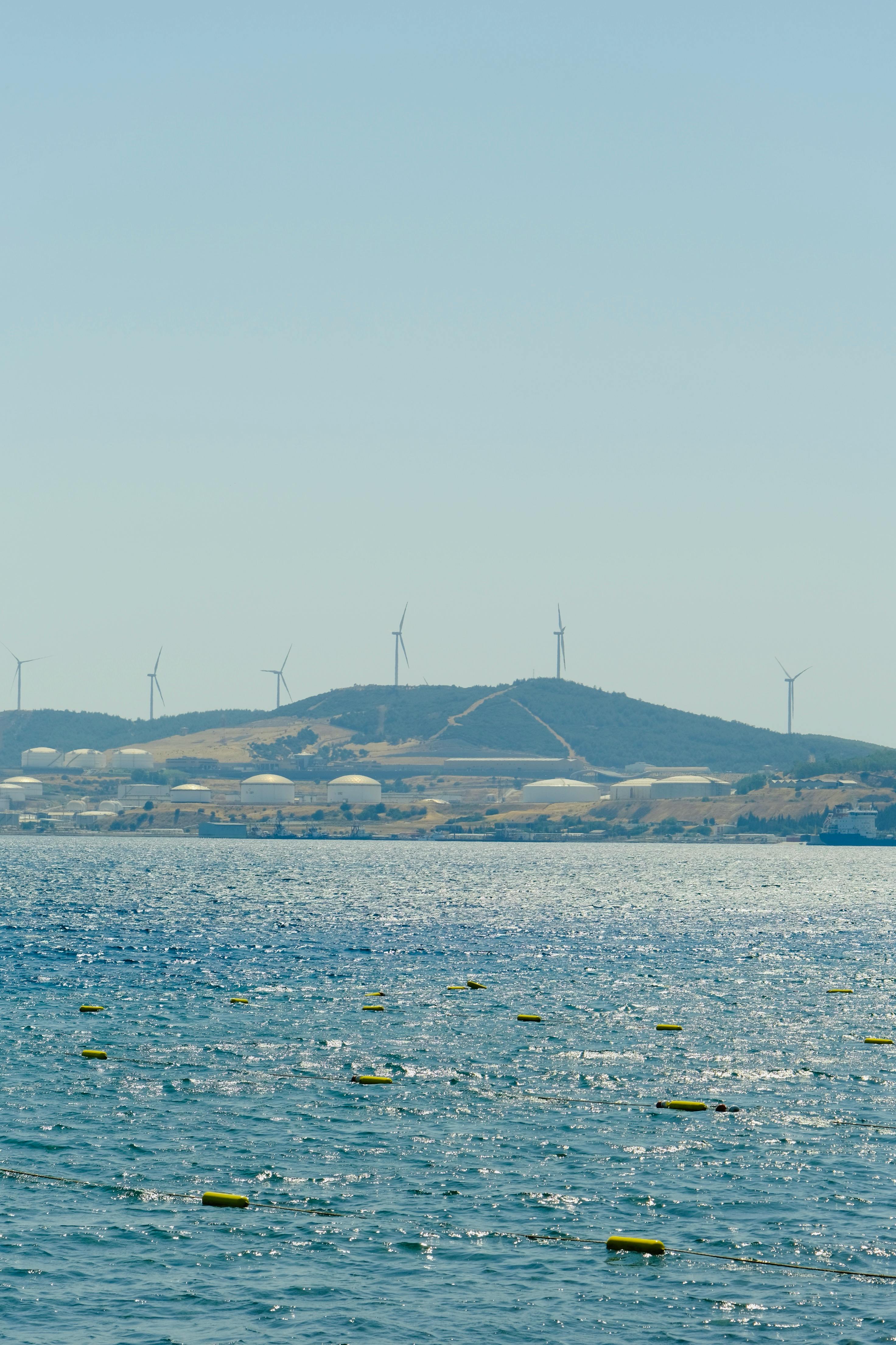 在晴朗的天气下，可以看到海洋和山上的风力涡轮机