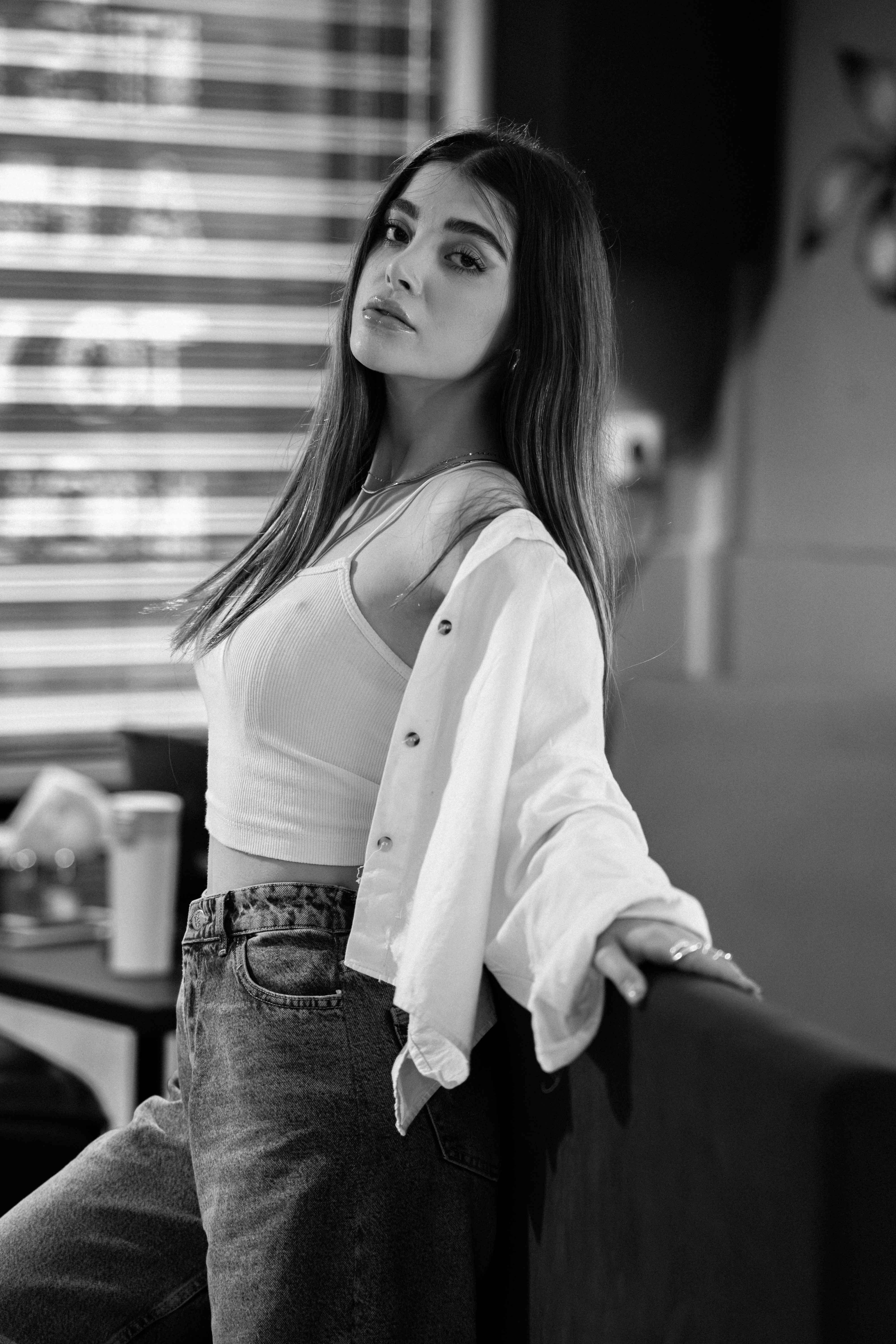 Black and white portrait of a woman posing stylishly indoors with a modern aesthetic.