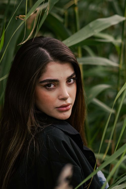 Free Captivating portrait of a woman surrounded by lush foliage, exuding a serene and natural vibe. Stock Photo
