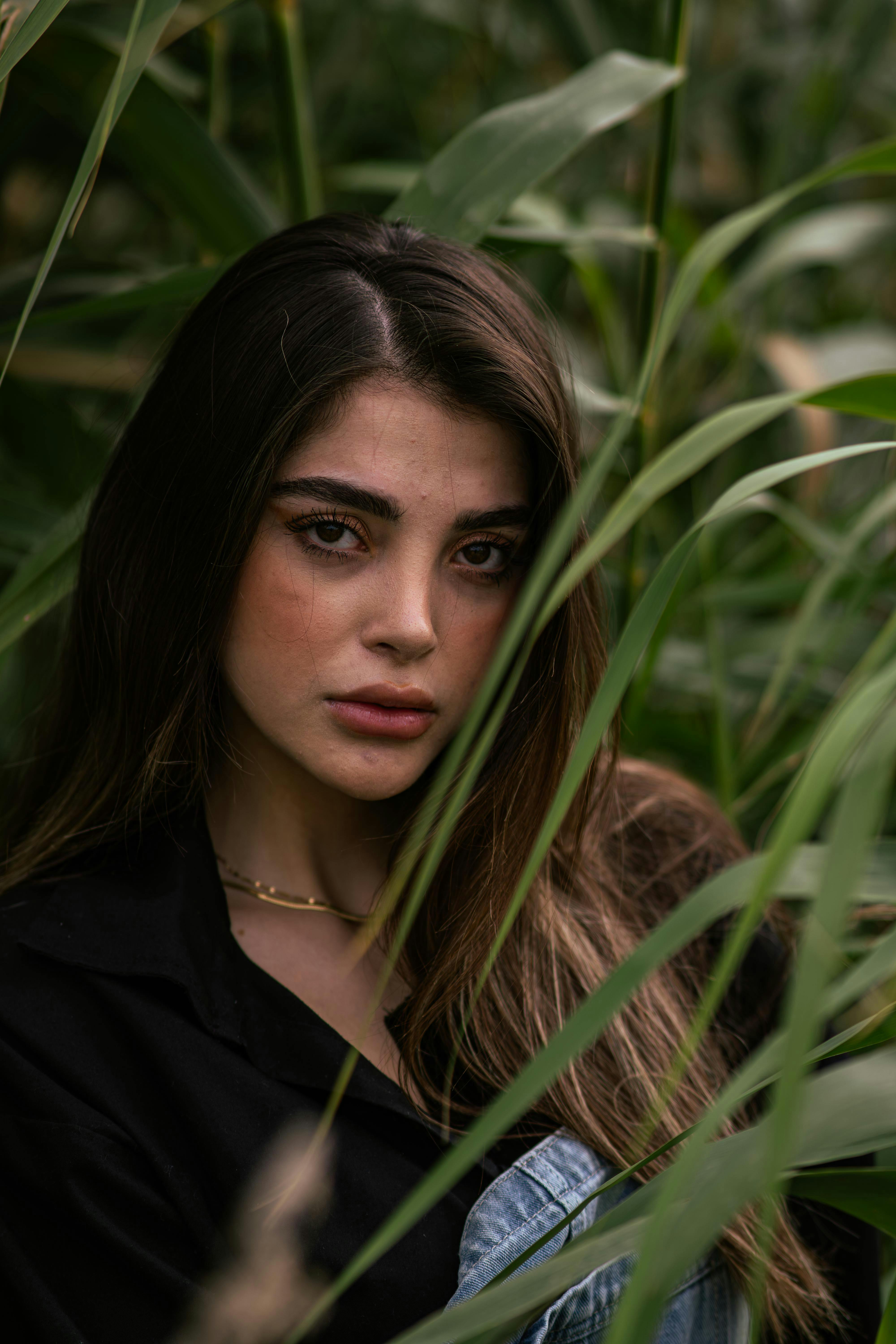 Kostenlos Ein heiteres Porträt einer Frau, umgeben von üppigem Grün, das natürliche Schönheit und Ruhe vermittelt. Stock-Foto