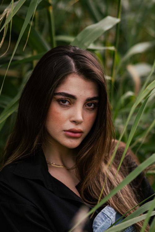Free A striking portrait of a woman with long hair surrounded by vibrant greenery, capturing a serene and natural atmosphere. Stock Photo