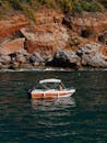 一艘小船在晴朗的天空下航行，土耳其的风景优美的岩石海岸线上