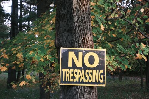 Free A no trespassing sign displayed on a tree surrounded by autumn foliage. Stock Photo
