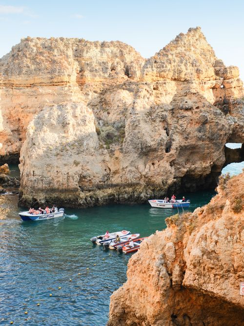 Free Scenic view of boats near golden cliffs and turquoise waters in Lagos, Portugal. Stock Photo