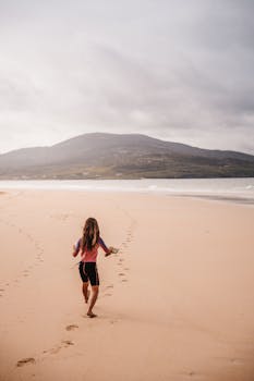 一个快乐的孩子沿着苏格兰哈里斯勒斯肯泰尔海滩的沙滩奔跑