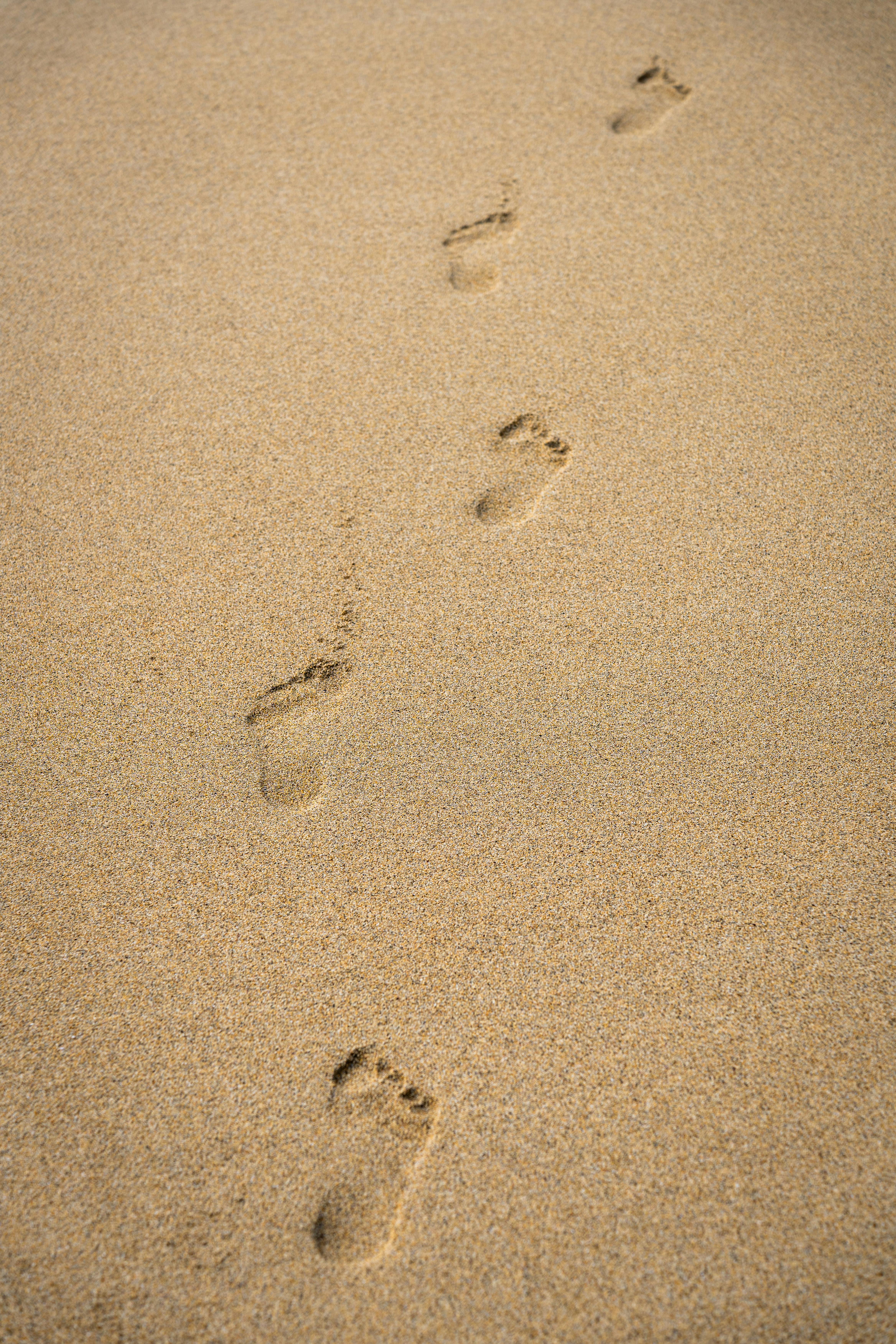 足迹在阳光明媚的沙滩上划过，捕捉到了苏格兰哈里斯的宁静