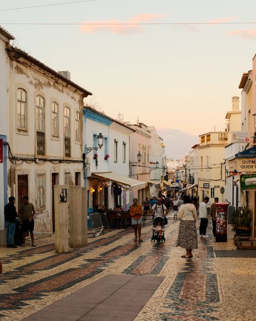 Free Explore the evening charm of Lagos, Portugal's cobblestone streets and pastel buildings during golden hour. Stock Photo
