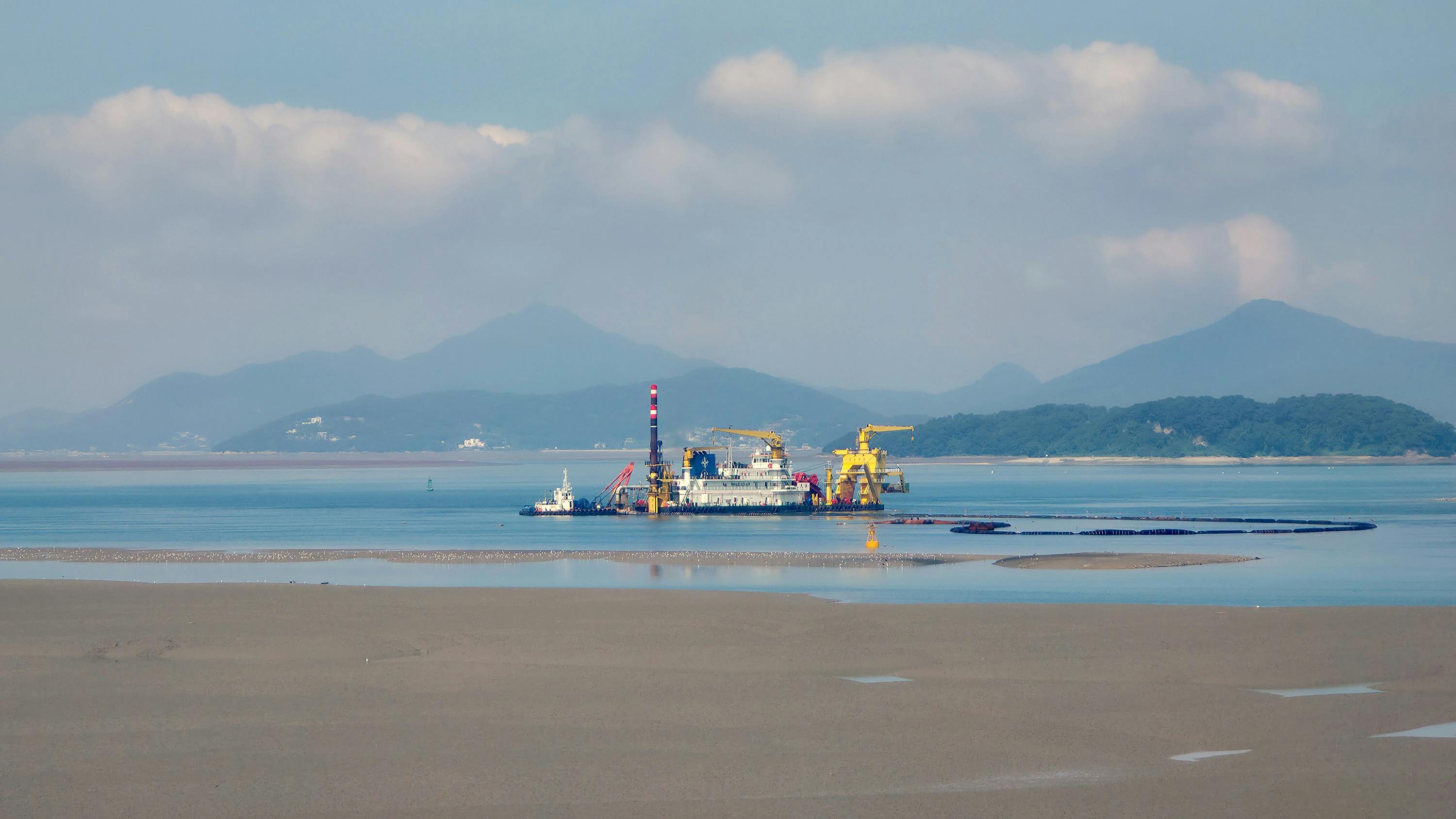 宁静的海景中，平静的水域上停靠着一艘疏浚船