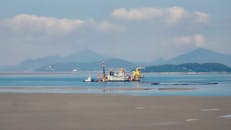 宁静的海景中，平静的水域上停靠着一艘疏浚船