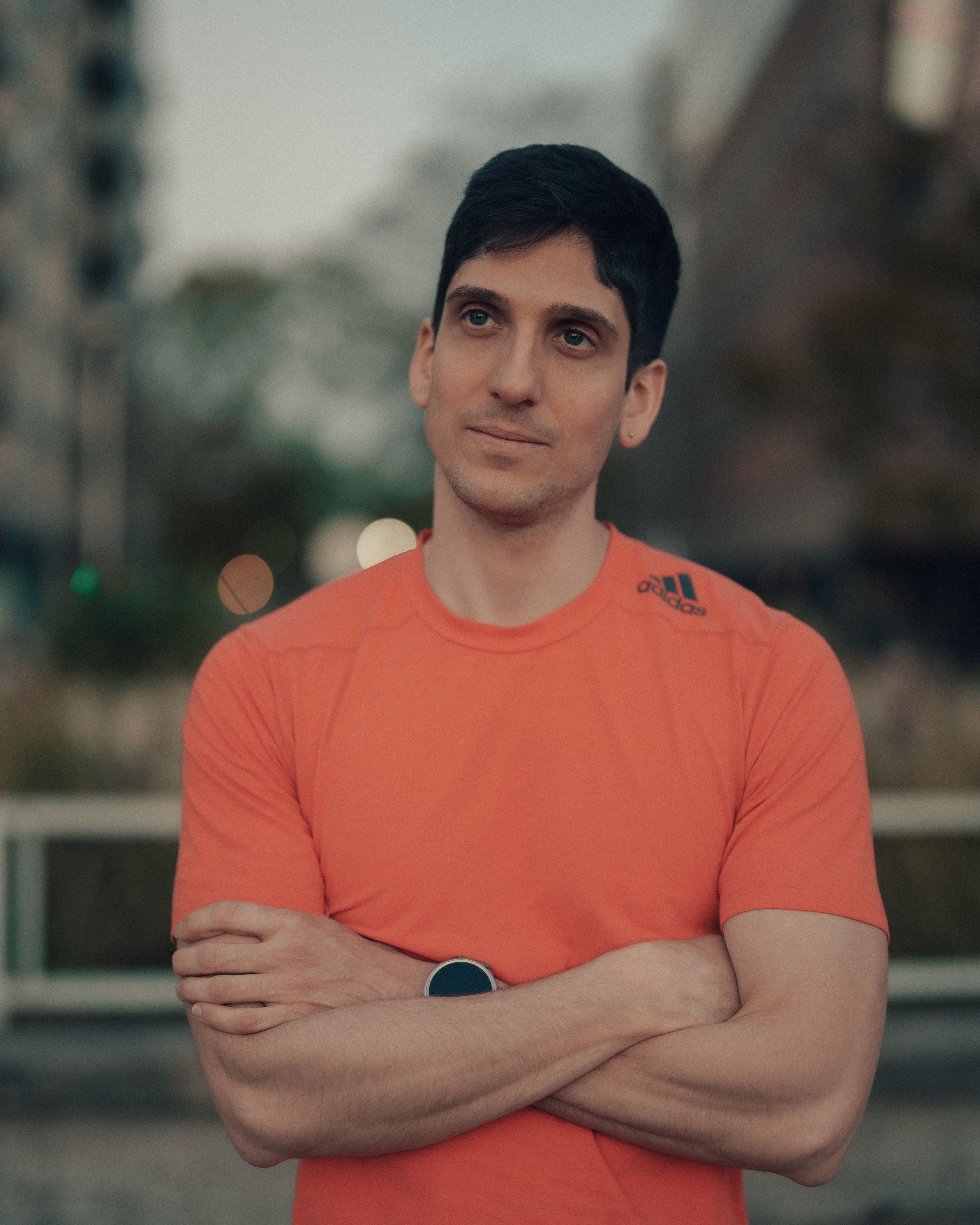 Contemplative man standing outdoors in Buenos Aires, wearing a bright orange shirt.