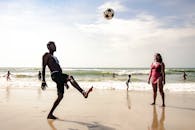 人们在圣保罗的海滩上享受热闹的一天，在海边踢足球