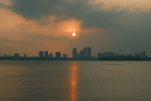 Calm sunset view of city skyline with sun reflection on water, Indore.