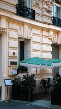 Cozy Parisian sidewalk cafe with green umbrellas and elegant architecture.