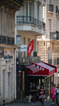 A bustling Paris street featuring a classic cafe and a neon tabac sign, capturing urban life.