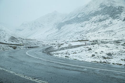Snow-covered mountain road in Curtea de Argeș, Romania, showcasing a serene winter landscape.