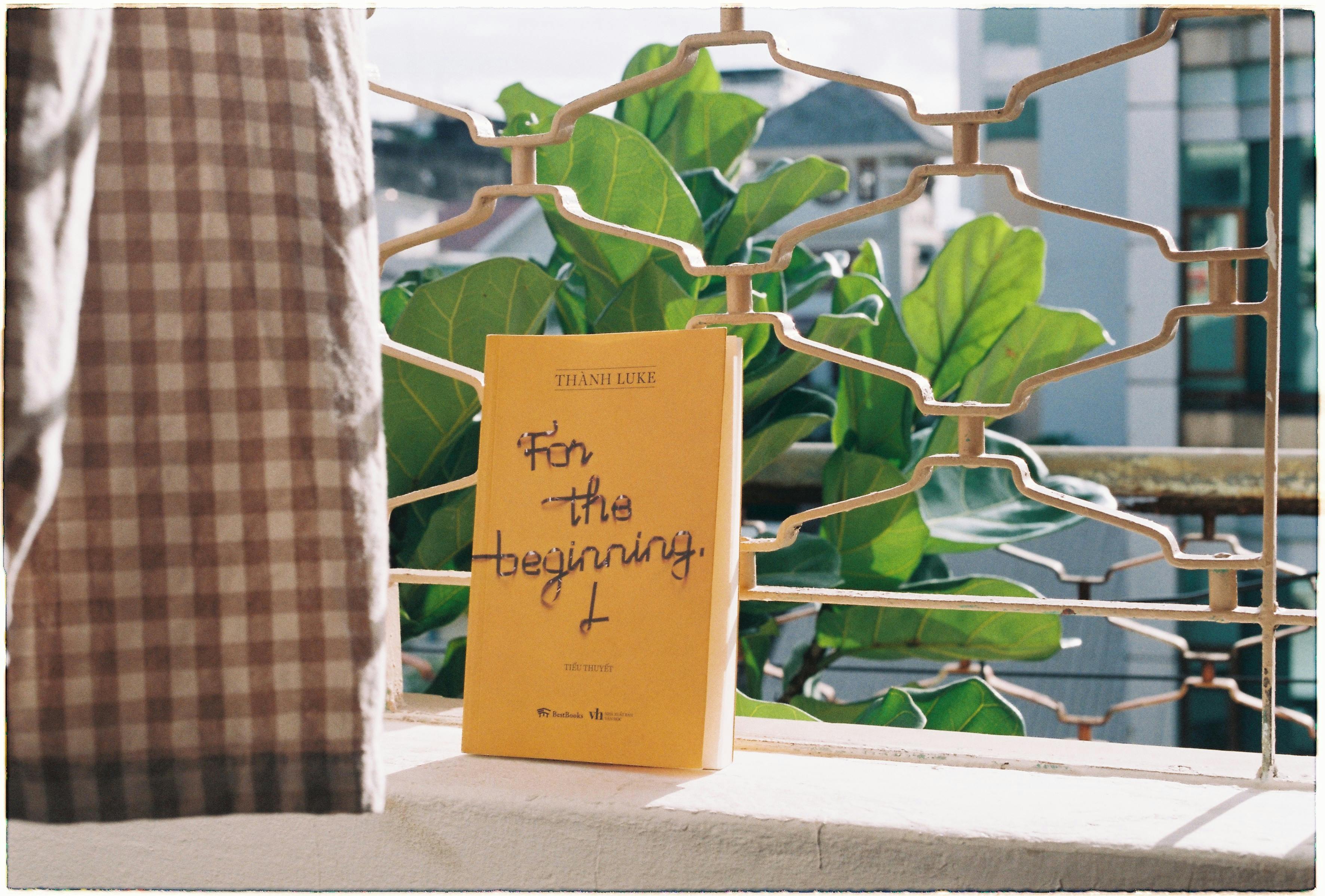A yellow book titled 'For the Beginning' displayed on a balcony, captured with natural light.