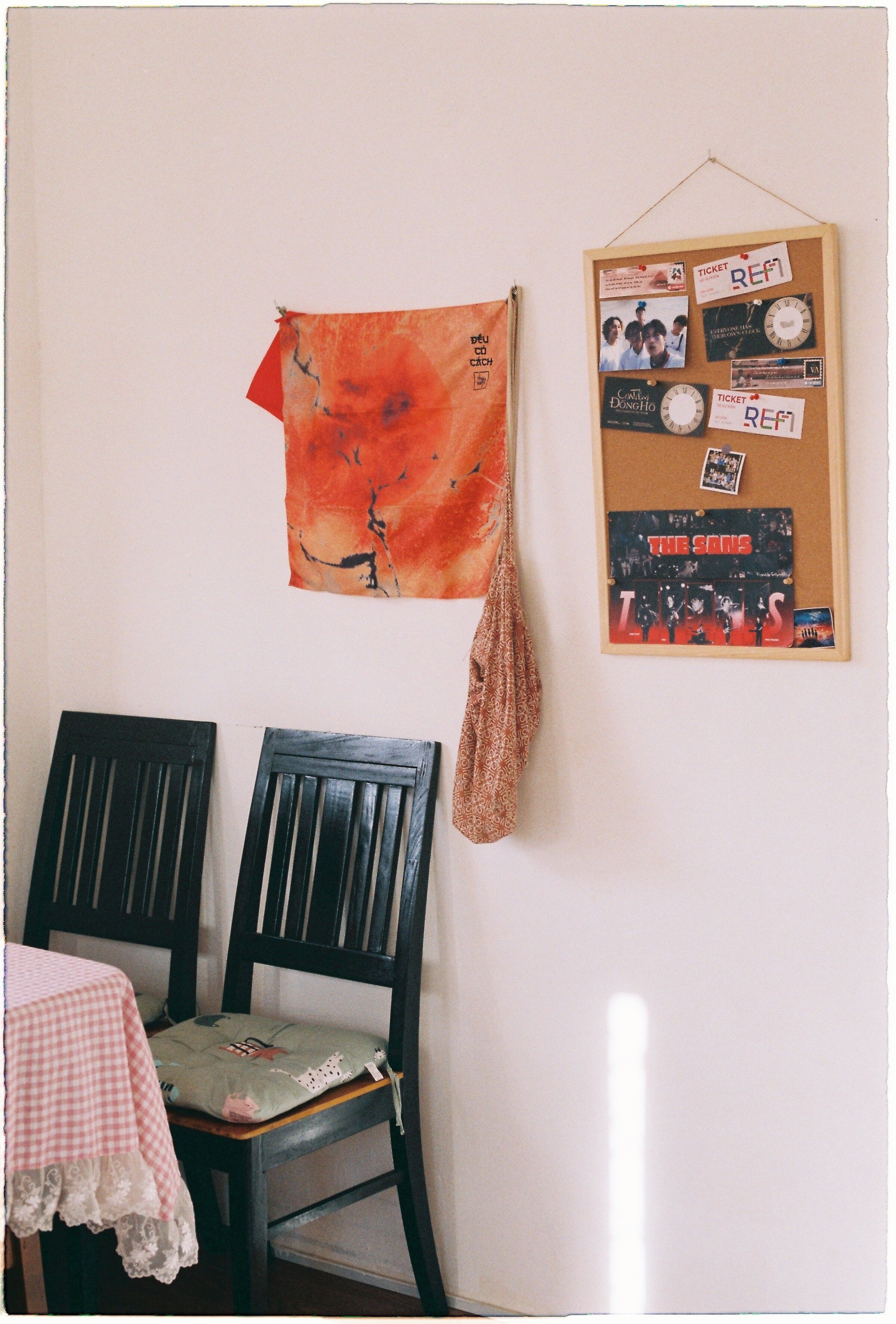 A cozy dining corner with chairs, wall art, and R.E.M. memorabilia on a bulletin board.
