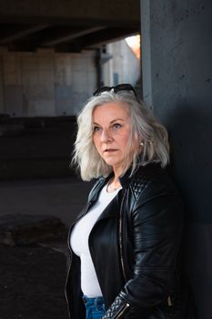Stylish mature woman with grey hair in a leather jacket outdoors.