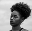 一幅引人注目的黑白肖像，一个女人在多云的天空下若有所思