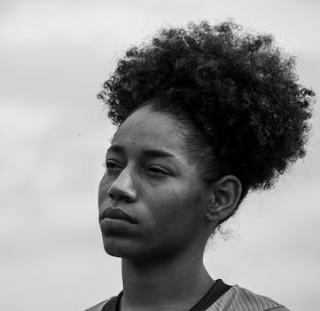 一幅引人注目的黑白肖像，一个女人在多云的天空下若有所思