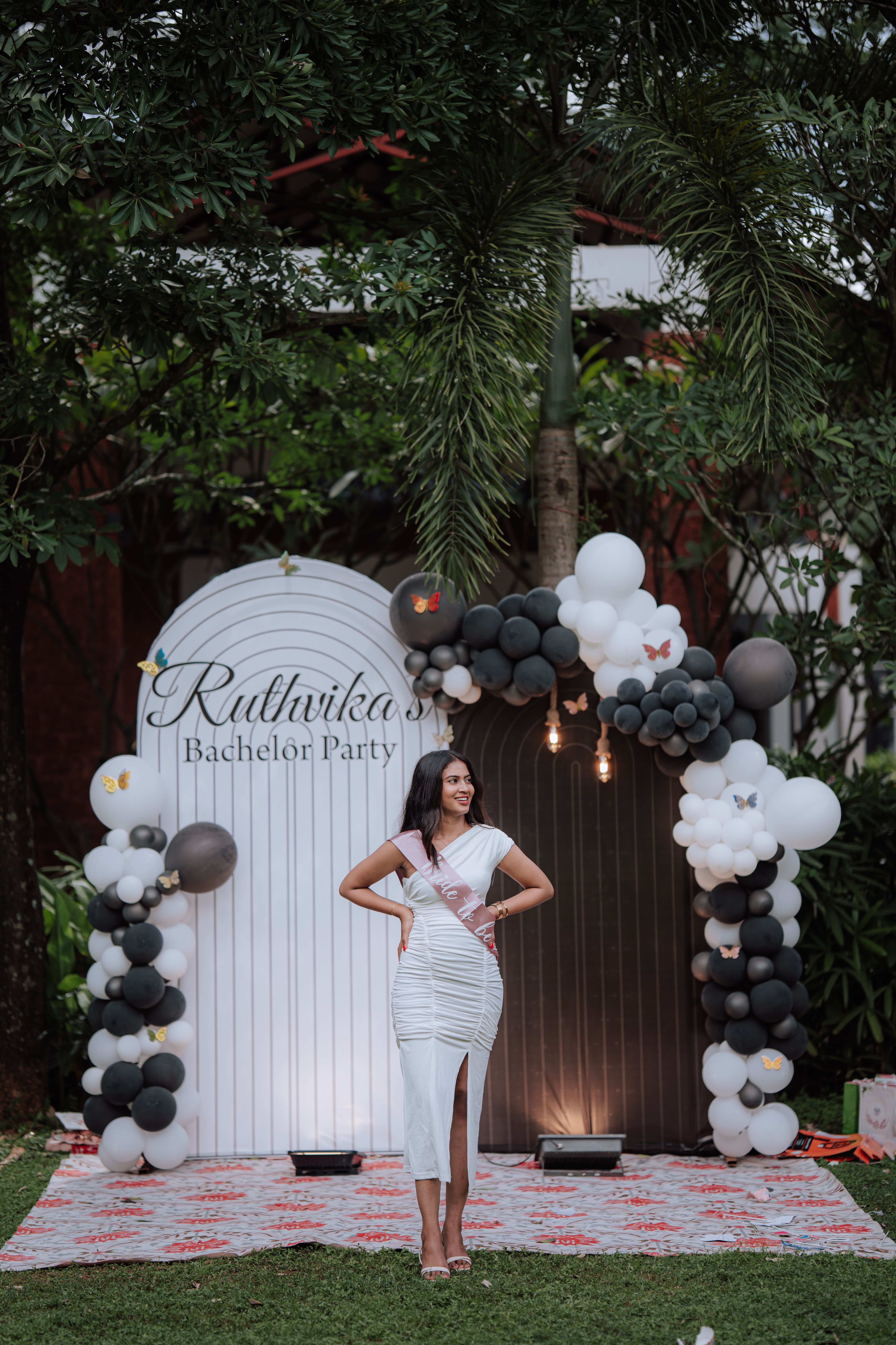 Woman at outdoor bachelorette party with elegant decor and balloons.
