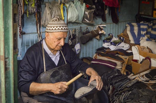 Elderly cobbler in a traditional workshop repairing shoes with precision in Kula, Türkiye.