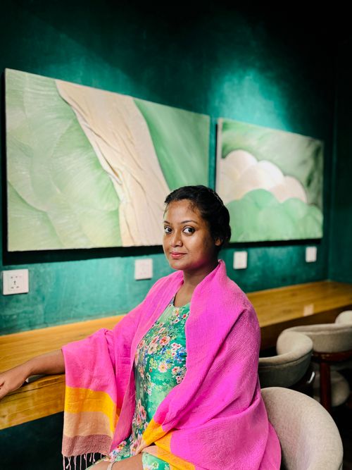 Free A woman enjoying a relaxed moment in a colorful art-filled cafe in Dhaka, Bangladesh. Stock Photo
