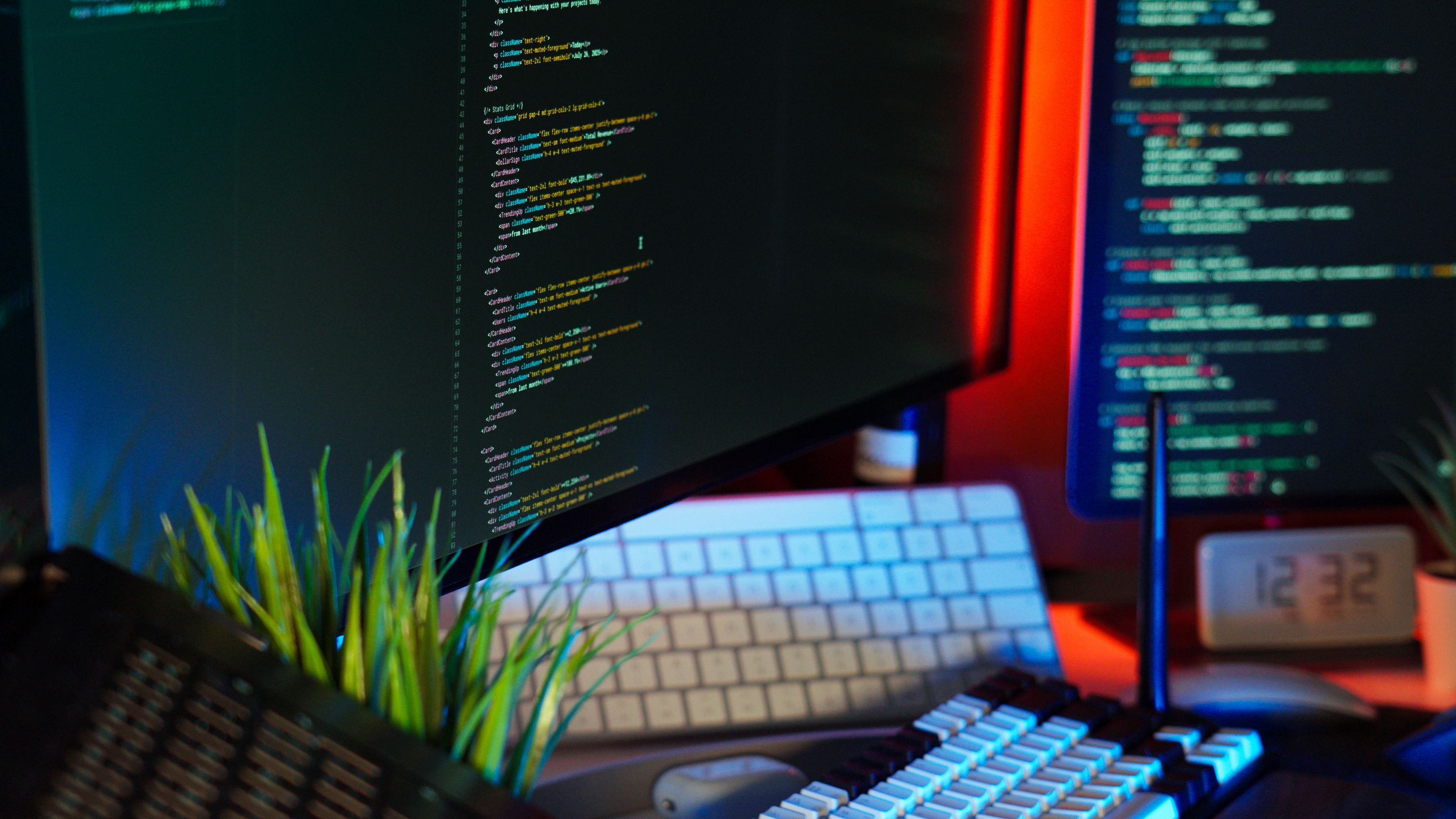 A vibrant workspace showing computer monitors with code, keyboard, and tech accessories.