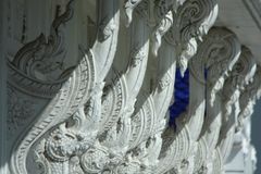 Ornate white carvings decorate a temple roof, showcasing intricate traditional design.