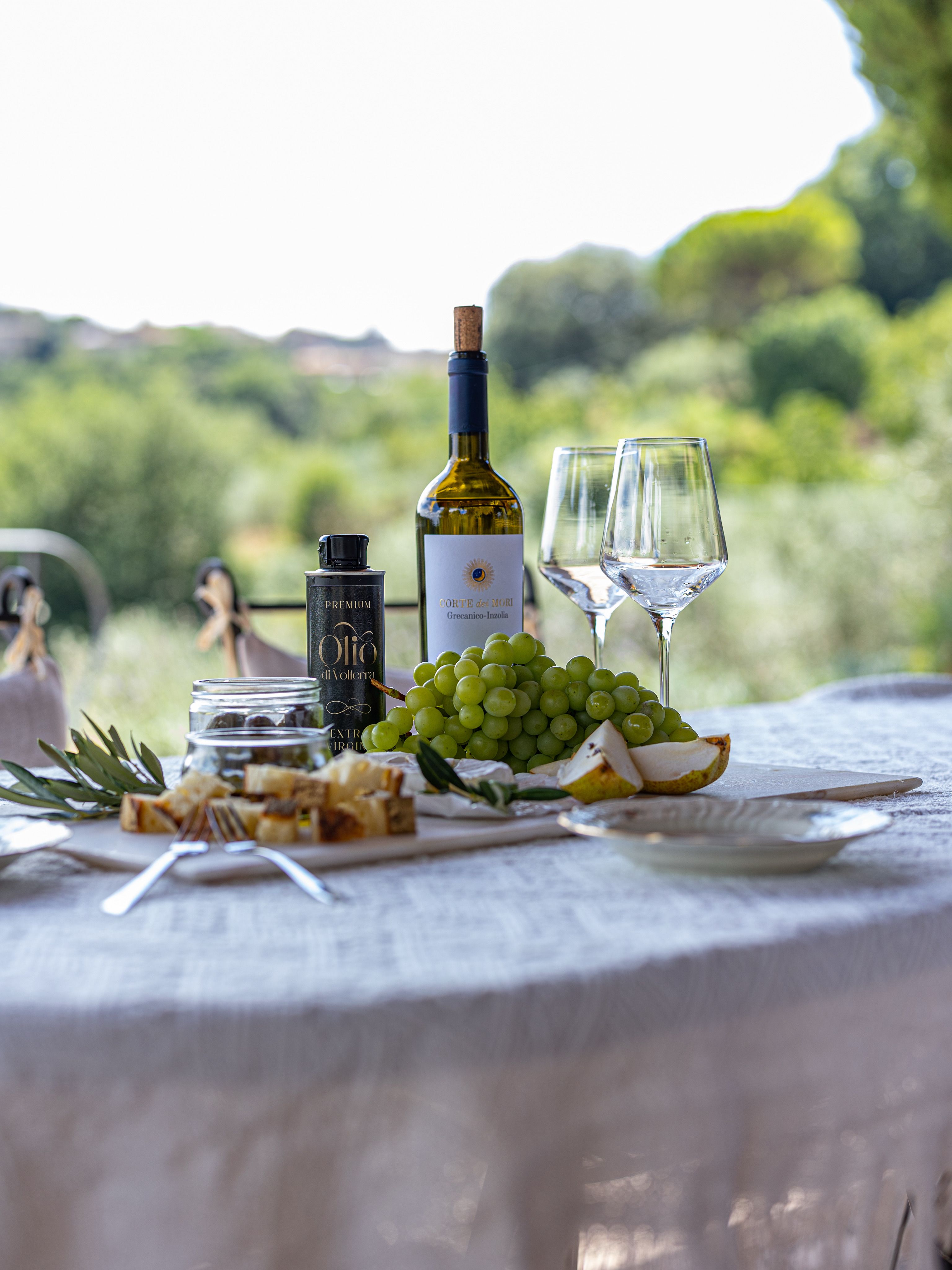 Elegant outdoor table setting with wine, cheese, and grapes.