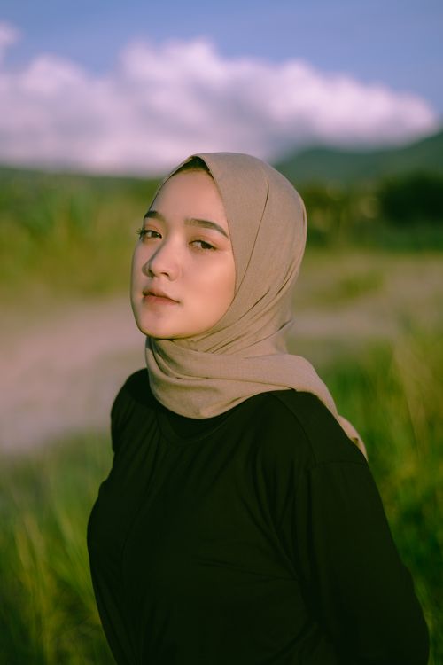 Free Elegant portrait of a woman in a hijab outdoors with a serene expression and natural landscape. Stock Photo