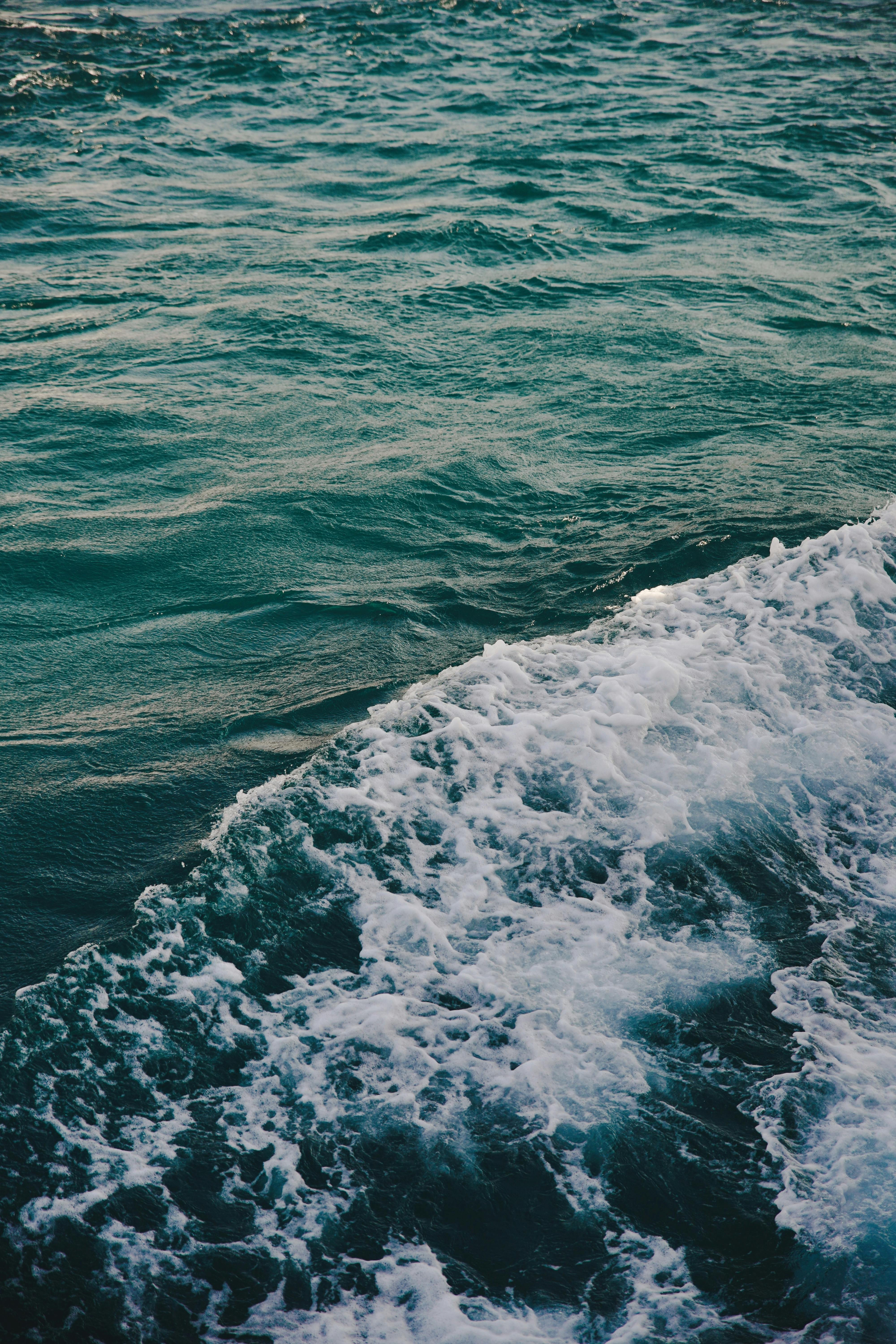 海浪沿着海面撞击的高角度视图，展现出充满活力的青色色调