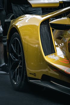 Detailed view of a yellow sports car featuring sleek black alloy wheels and aerodynamic design.