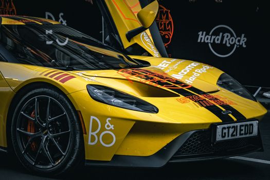 Dynamic close-up of a yellow sports car with vibrant graphics at a car show.