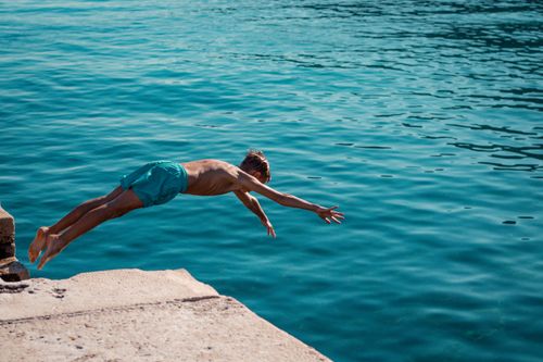 Free Captivating shot of a boy mid-dive into the clear Adriatic Sea in Lovran, Croatia, showcasing summer adventure. Stock Photo