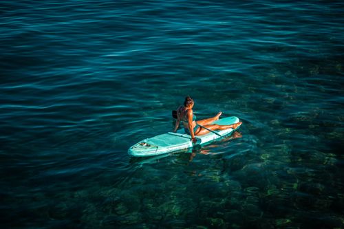 Free A woman enjoys a sunny day on a paddleboard in the clear Adriatic Sea near Lovran, Croatia. Stock Photo