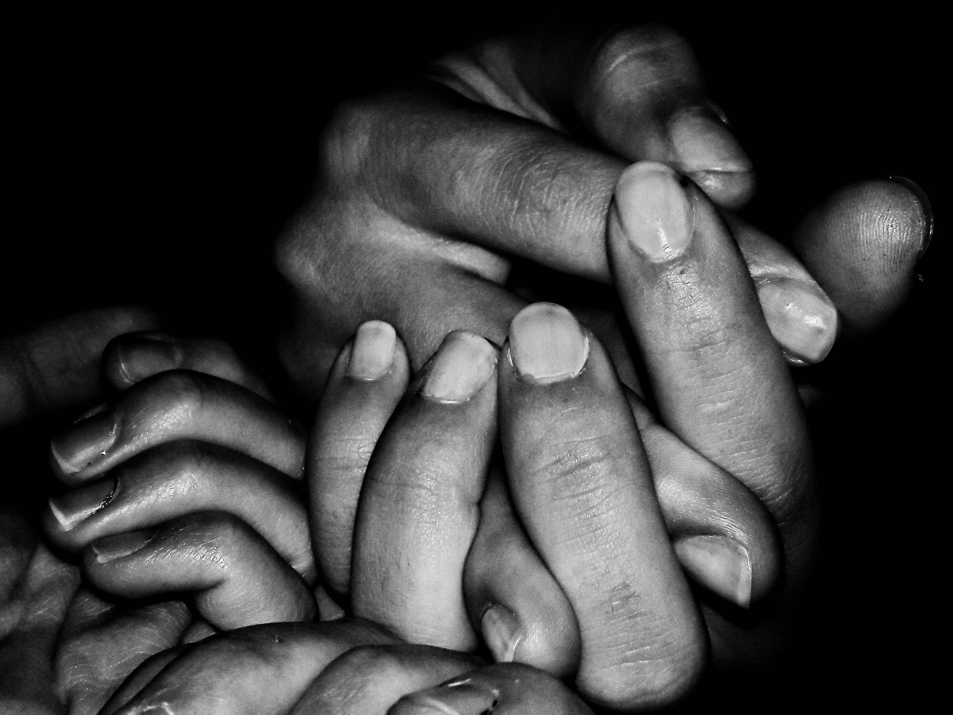 A black and white close-up of family hands holding each other, symbolizing unity and support.