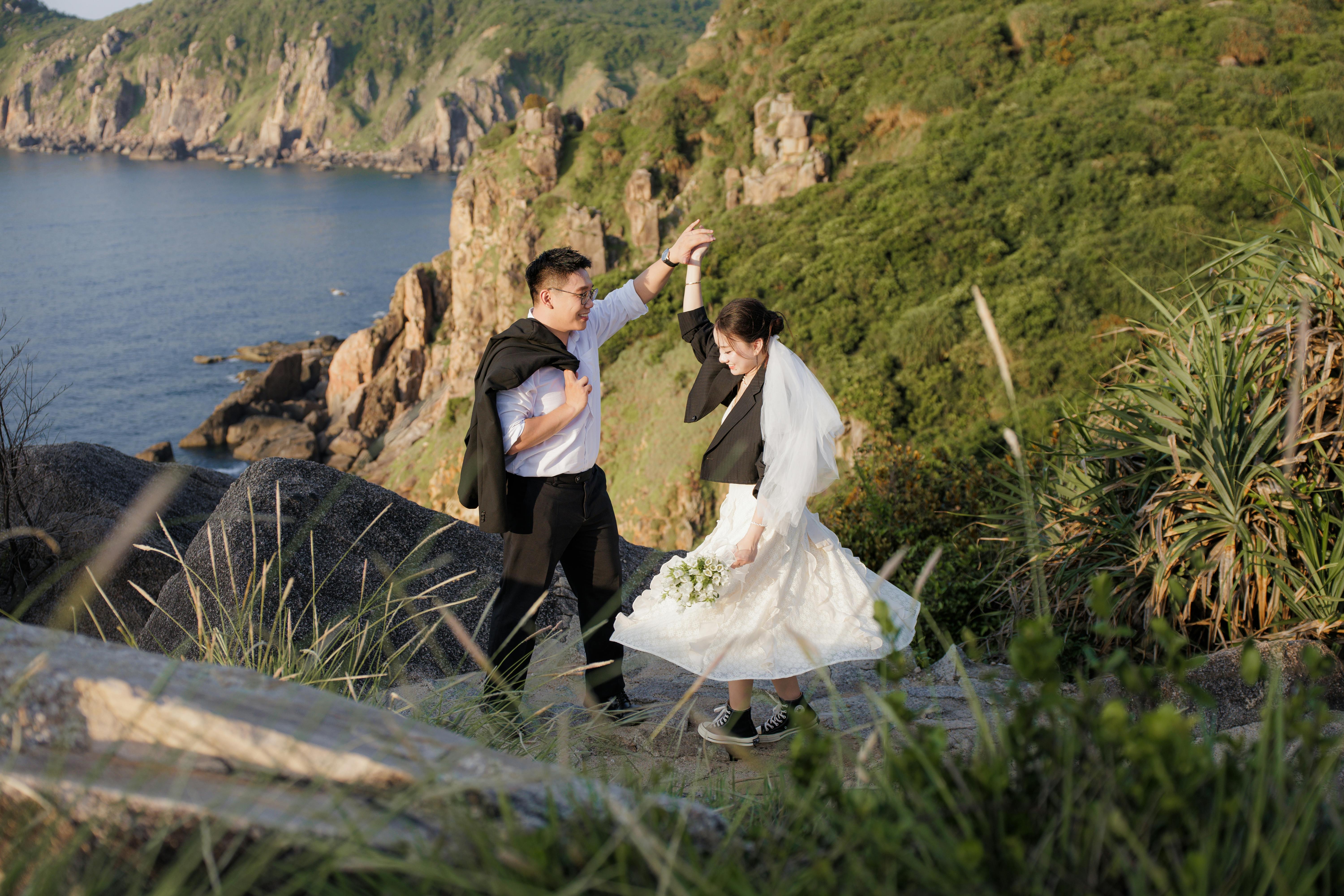 新娘和新郎在岩石峭壁上欣赏风景优美的海岸婚礼舞蹈