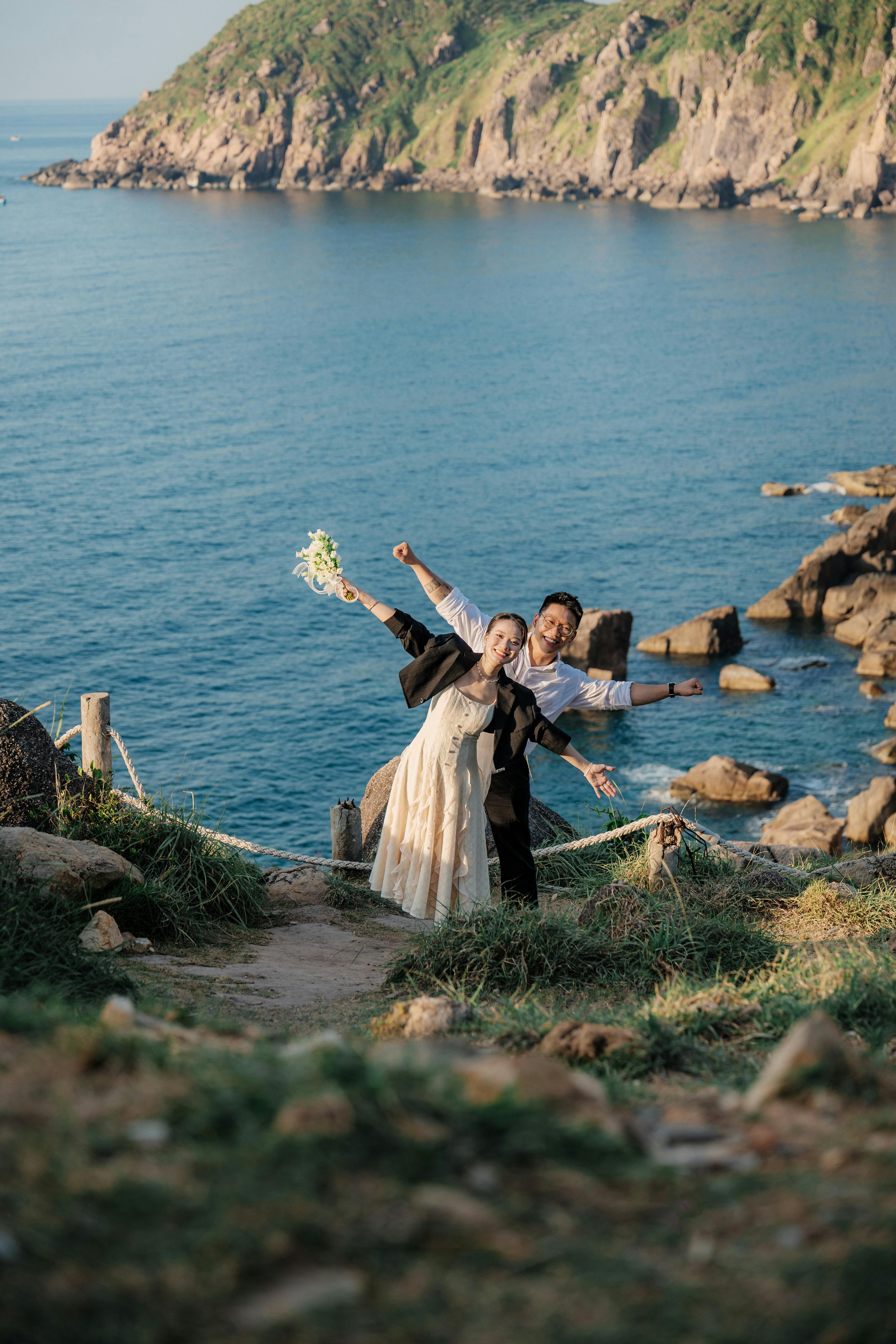 一对夫妇在海岸悬崖上愉快地摆姿势，以海洋和悬崖为背景