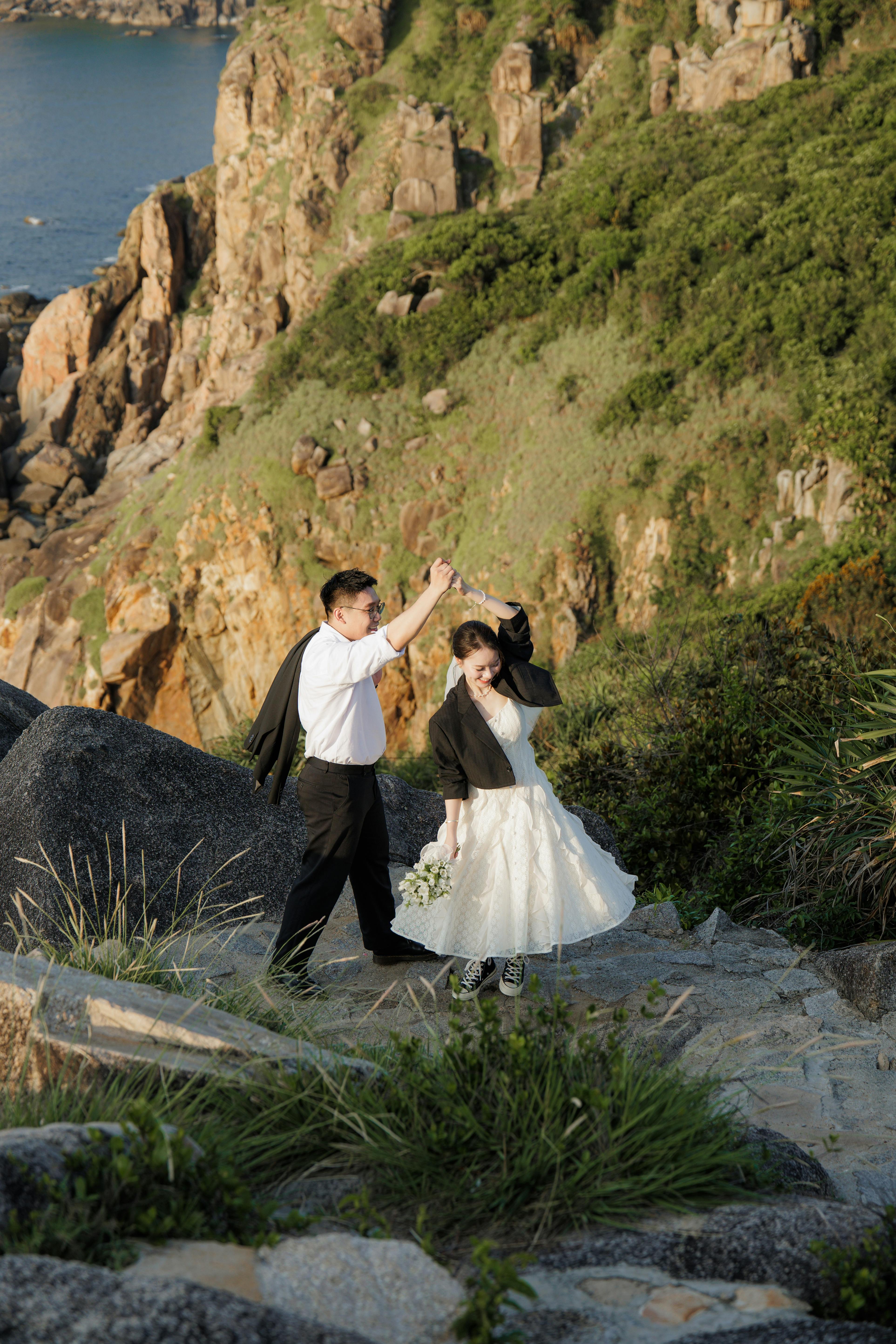 在日落时分，一对浪漫的情侣在岩石悬崖边跳舞，欣赏风景