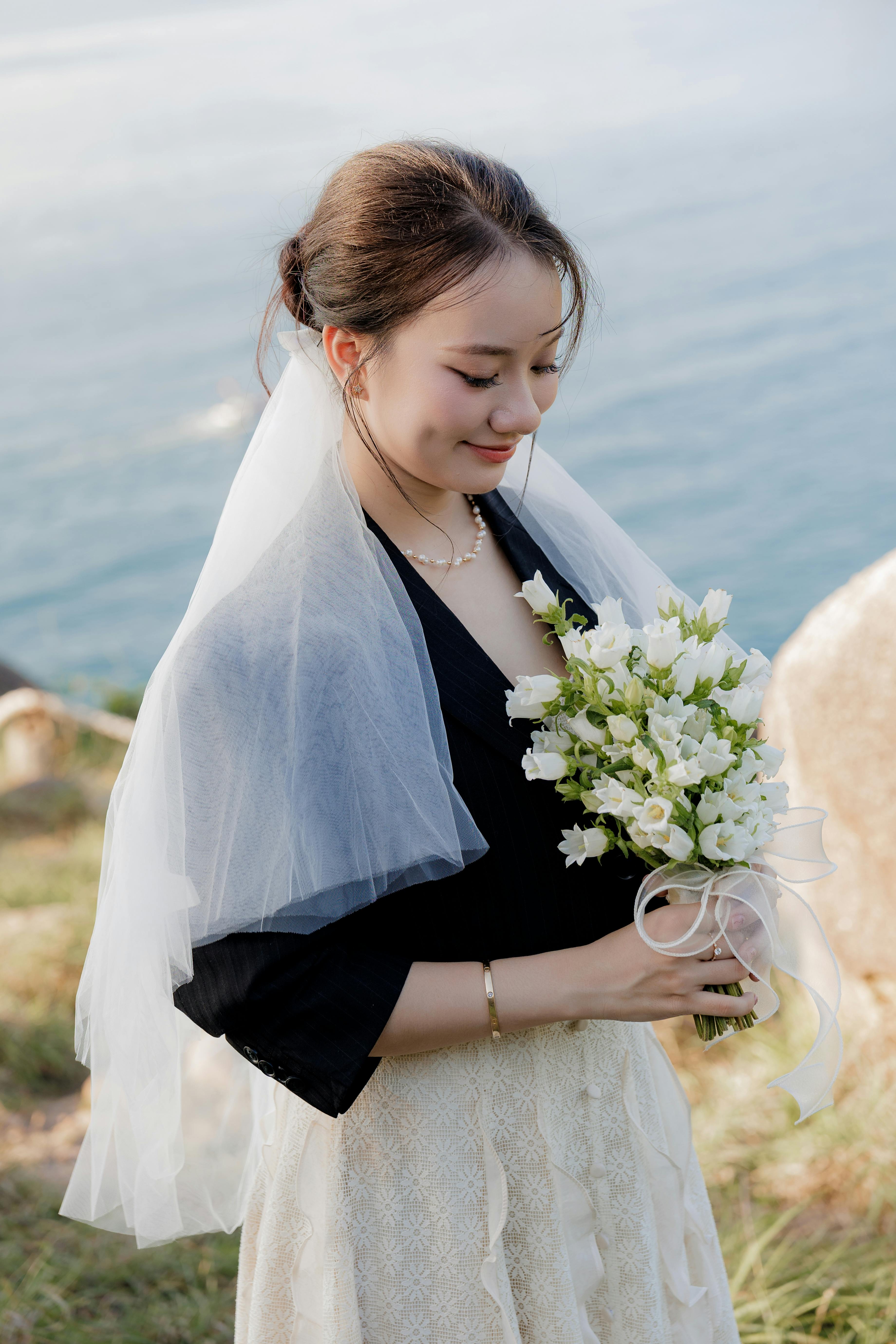 新娘在宁静的海边，手持白色花束，散发着优雅的气息