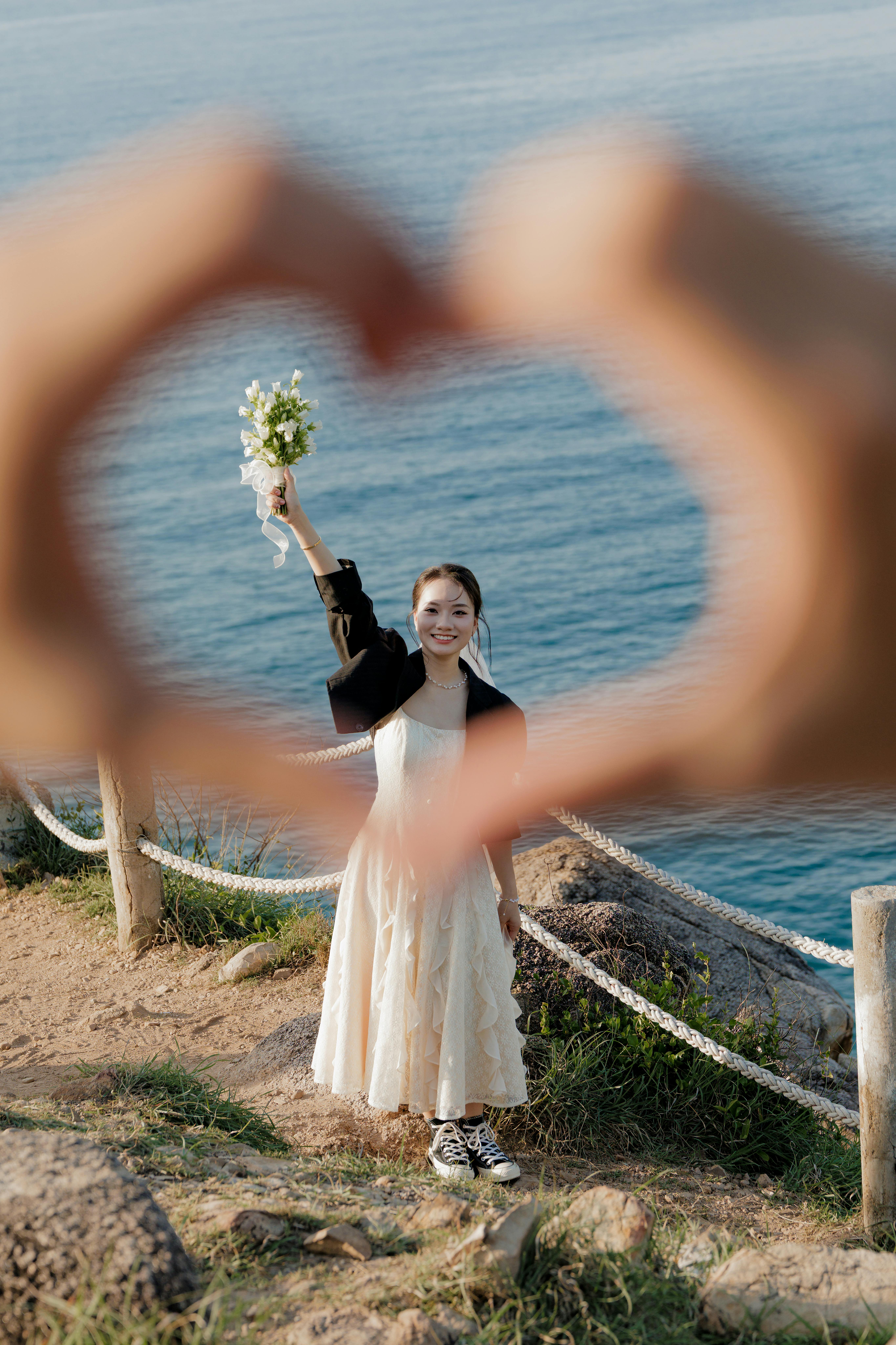 新娘微笑着，用双手勾勒出海景的轮廓