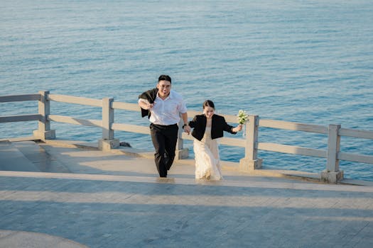 一对穿着正装的夫妇在海边散步，手牵着手，快乐地微笑