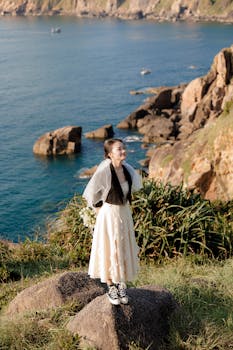 在阳光明媚的日子里，新娘穿着白色连衣裙和运动鞋，站在海边的岩石上