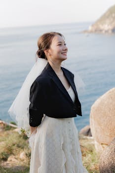 身穿婚纱的优雅新娘站在海边，轻声微笑
